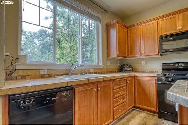 9575 SW Tephra Ter, Beaverton, OR 97007 - kitchen with black appliances, a sink, healthy amount of natural light, and light wood-style flooring