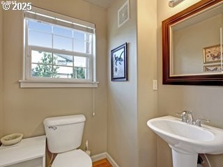 bathroom with toilet, a sink, and baseboards