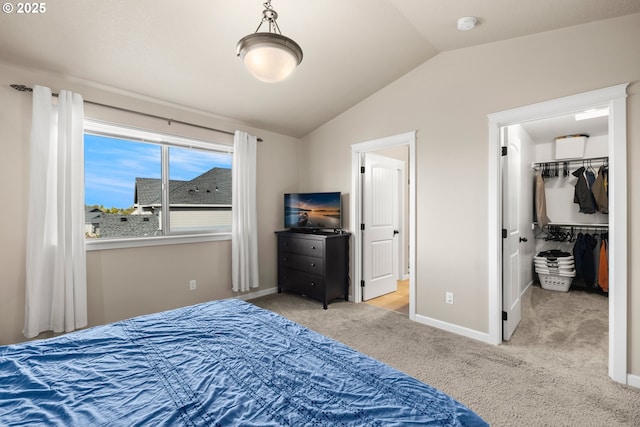 bedroom featuring a spacious closet, lofted ceiling, carpet flooring, and baseboards