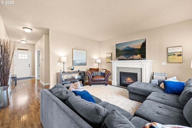 living room featuring baseboards, wood finished floors, and a tiled fireplace