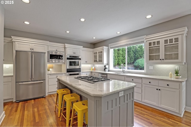 kitchen with stainless steel appliances, decorative backsplash, a center island, white cabinets, and recessed lighting
