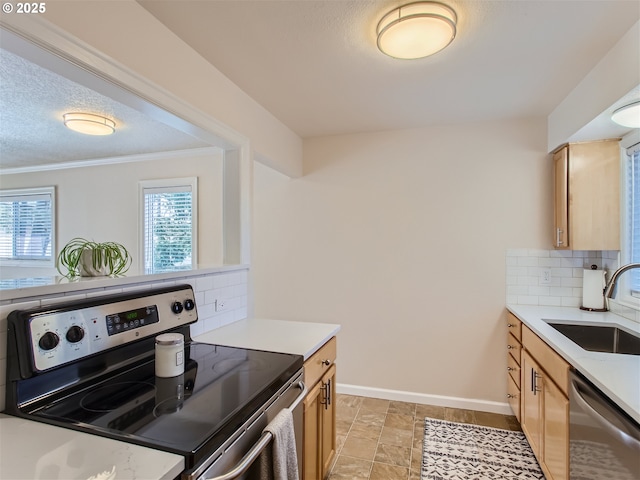 kitchen with tasteful backsplash, baseboards, light countertops, stainless steel appliances, and a sink