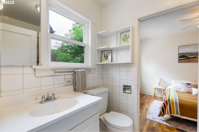 3905 SE 54th Ave, Portland, OR 97206 - bathroom featuring toilet, wood finished floors, vanity, backsplash, and tile walls