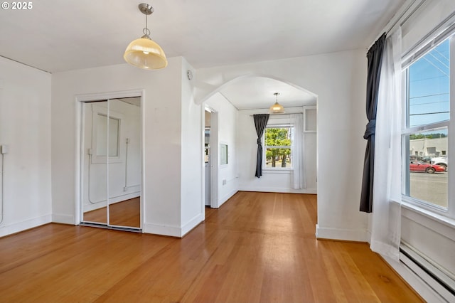 3905 SE 54th Ave, Portland, OR 97206 - unfurnished dining area with a baseboard radiator, arched walkways, light wood-type flooring, and baseboards