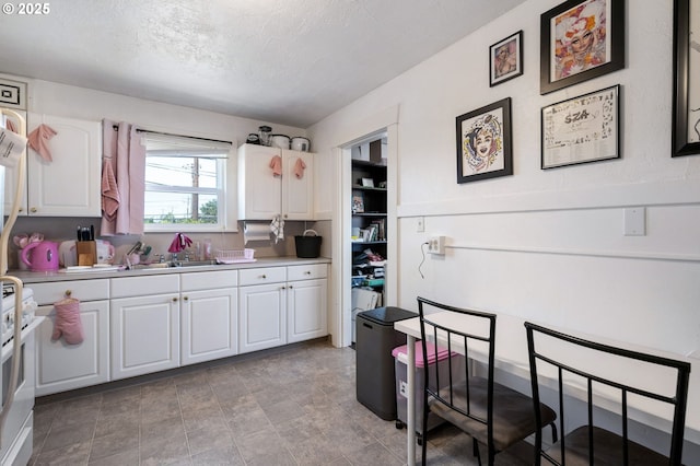 3905 SE 54th Ave, Portland, OR 97206 - kitchen with white cabinetry, a sink, light countertops, a textured ceiling, and white gas range oven