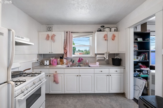 3905 SE 54th Ave, Portland, OR 97206 - kitchen featuring white appliances, a sink, under cabinet range hood, light countertops, and white cabinets