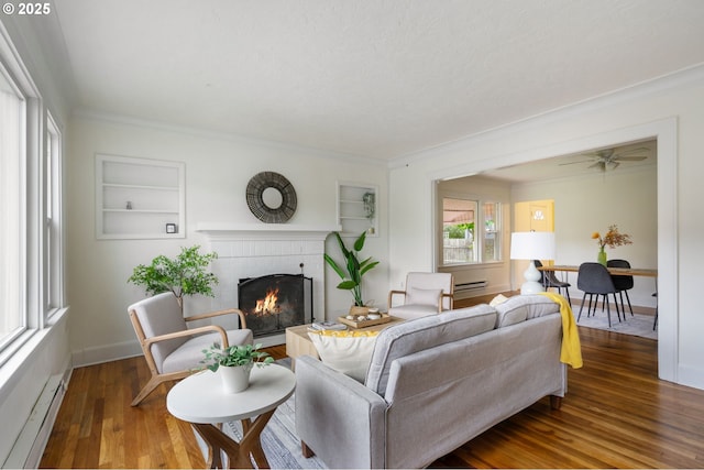 3905 SE 54th Ave, Portland, OR 97206 - living room featuring a brick fireplace, wood finished floors, built in features, baseboard heating, and ornamental molding
