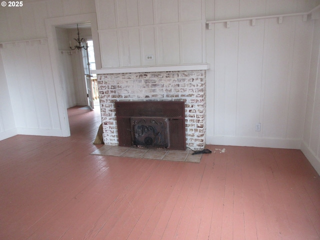 328 6th Ave, Seaside, OR 97138 - unfurnished living room featuring hardwood / wood-style flooring, a brick fireplace, a decorative wall, and baseboards