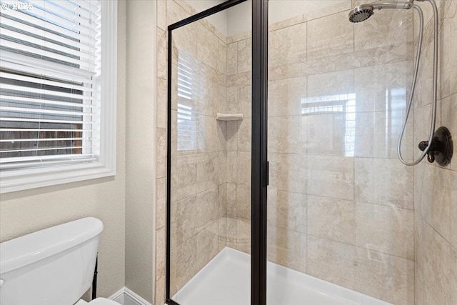 bathroom with a shower with door and toilet