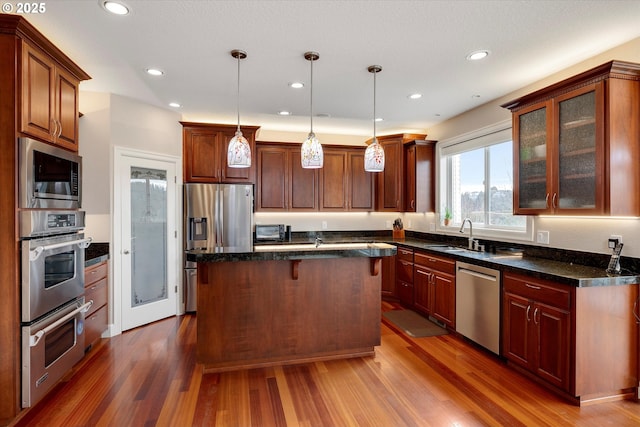 kitchen featuring a center island, sink, stainless steel appliances, dark hardwood / wood-style flooring, and decorative light fixtures