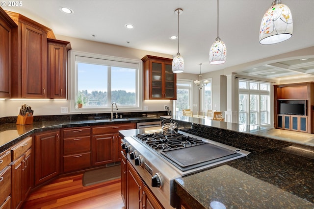 kitchen with sink, hanging light fixtures, light hardwood / wood-style flooring, gas stovetop, and dark stone countertops