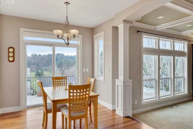 dining space featuring a chandelier, light wood-type flooring, and decorative columns