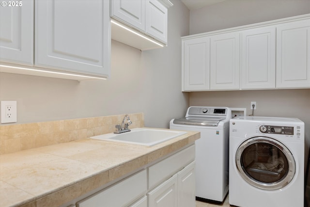 laundry area with cabinets, washer and clothes dryer, and sink