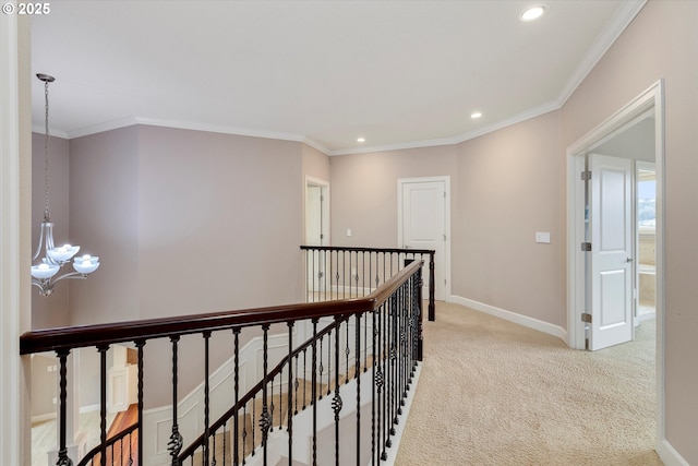 hall with a chandelier, light colored carpet, and ornamental molding