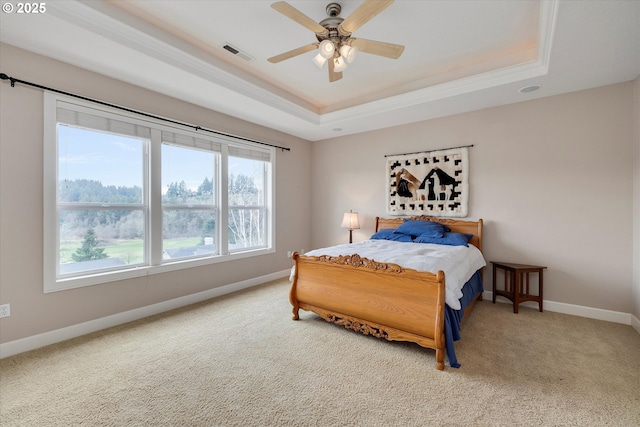 carpeted bedroom featuring ceiling fan, ornamental molding, and a tray ceiling