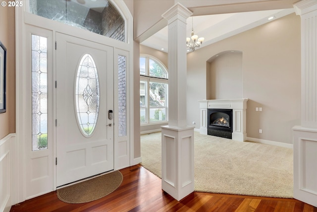 entryway with a chandelier, wood-type flooring, decorative columns, and plenty of natural light