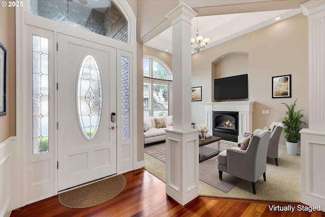 foyer entrance featuring decorative columns, a chandelier, and hardwood / wood-style flooring