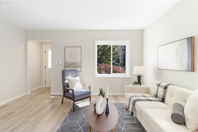 living area with light wood-type flooring, visible vents, and baseboards