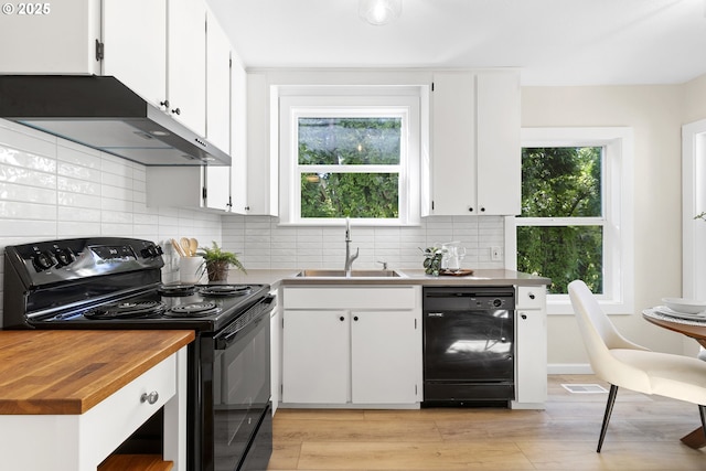 kitchen featuring decorative backsplash, light wood-style flooring, under cabinet range hood, black appliances, and a sink