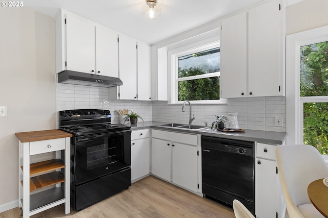 kitchen featuring light wood-style flooring, under cabinet range hood, a sink, white cabinetry, and black appliances