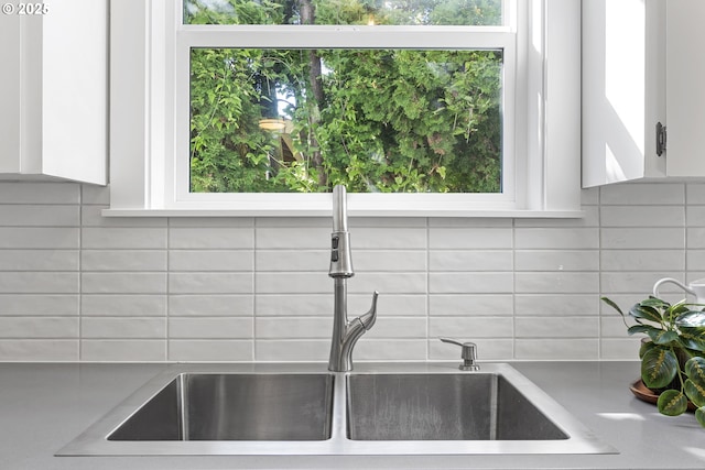 interior details with light countertops, tasteful backsplash, a sink, and white cabinetry