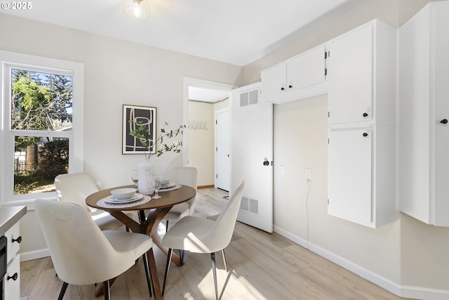 dining area featuring light wood-style floors, baseboards, and visible vents