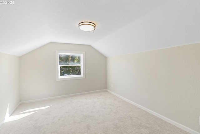 bonus room featuring a textured ceiling, vaulted ceiling, carpet flooring, and baseboards