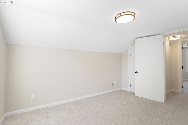 additional living space featuring light colored carpet, vaulted ceiling, visible vents, and baseboards