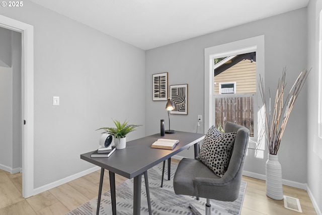 office space featuring light wood finished floors, baseboards, and visible vents