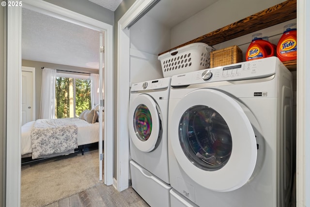 27650 SW Canyon Creek Rd, Wilsonville, OR 97070 - washroom featuring washer and clothes dryer, light wood-style flooring, and a textured ceiling
