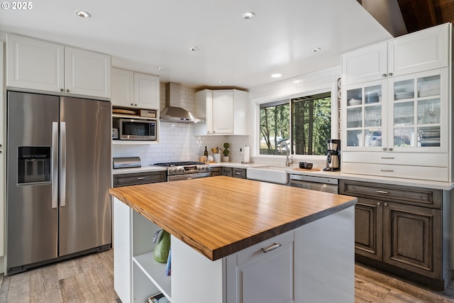 27650 SW Canyon Creek Rd, Wilsonville, OR 97070 - kitchen with appliances with stainless steel finishes, wall chimney exhaust hood, light wood-style flooring, white cabinets, and a sink