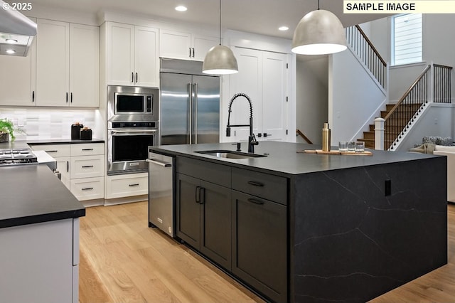 2285 Satter St, West Linn, OR 97068 - kitchen with built in appliances, dark countertops, a sink, light wood-style flooring, and white cabinetry