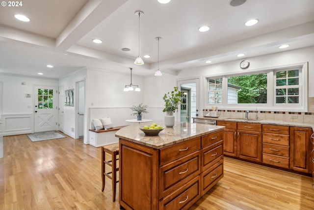 kitchen with light hardwood / wood-style floors, sink, decorative light fixtures, a kitchen island, and beamed ceiling