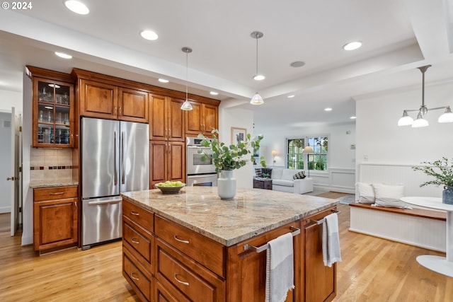 kitchen featuring appliances with stainless steel finishes, decorative backsplash, light stone countertops, a kitchen island, and pendant lighting