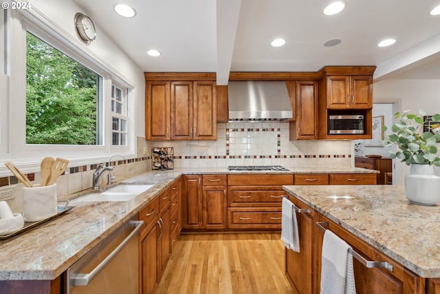 kitchen with backsplash, light hardwood / wood-style floors, sink, stainless steel appliances, and wall chimney exhaust hood