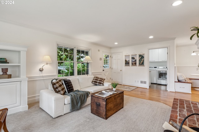 living room with crown molding, light hardwood / wood-style flooring, and washing machine and clothes dryer