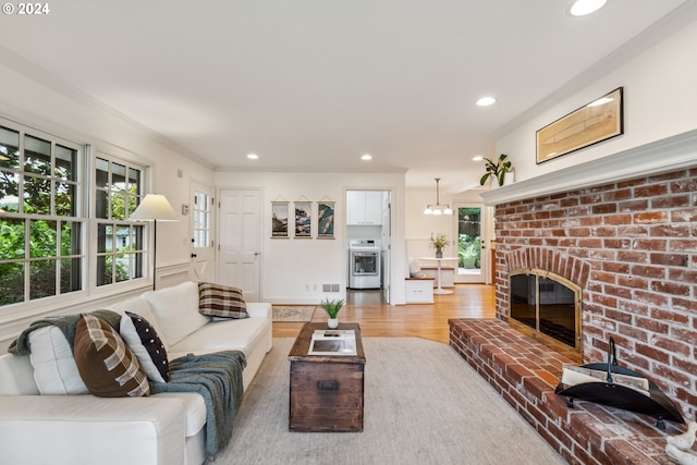 living room with a brick fireplace, hardwood / wood-style flooring, and ornamental molding