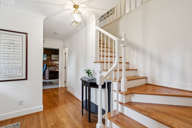 stairs featuring a fireplace, ornamental molding, and hardwood / wood-style flooring