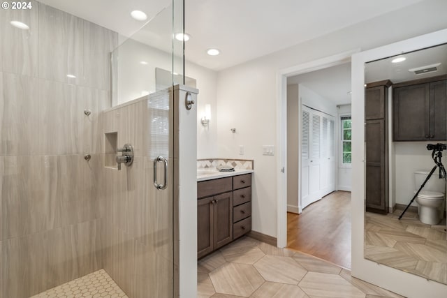 bathroom with toilet, tile patterned flooring, a shower with shower door, and vanity