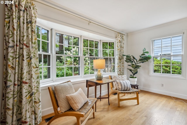 sitting room with ornamental molding and light hardwood / wood-style floors