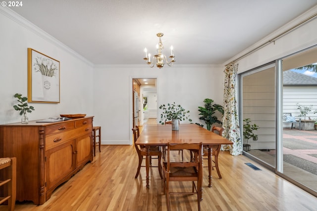 dining area featuring light hardwood / wood-style flooring, ornamental molding, and a notable chandelier