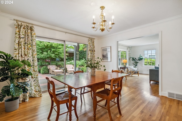 dining area featuring a chandelier, ornamental molding, and light hardwood / wood-style flooring