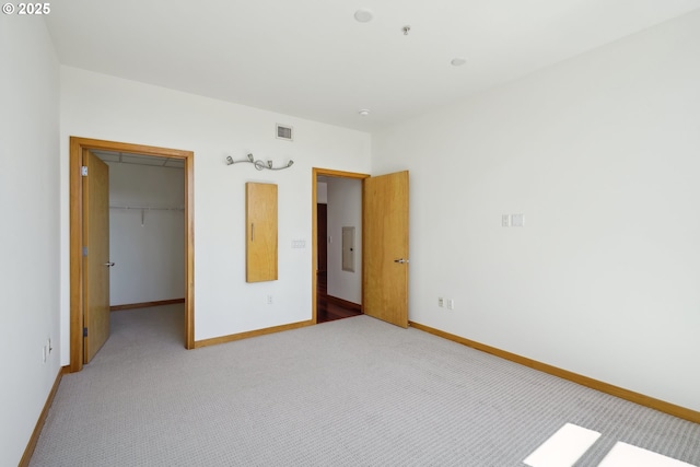 unfurnished bedroom with carpet flooring, a spacious closet, baseboards, and a closet