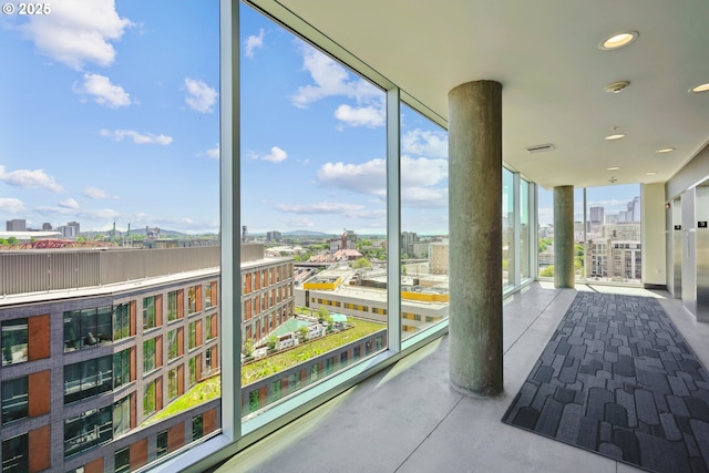 unfurnished sunroom with a city view, finished concrete flooring, expansive windows, and recessed lighting
