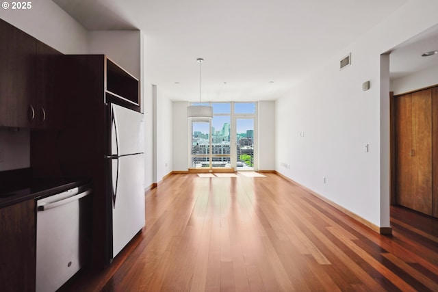 kitchen featuring freestanding refrigerator, dishwashing machine, wood finished floors, baseboards, and expansive windows