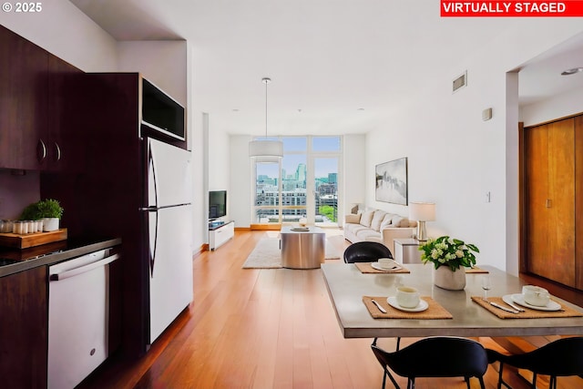 kitchen with white appliances, light wood finished floors, modern cabinets, and hanging light fixtures