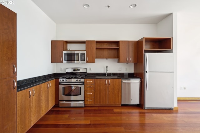 kitchen featuring open shelves, appliances with stainless steel finishes, a sink, dark countertops, and recessed lighting