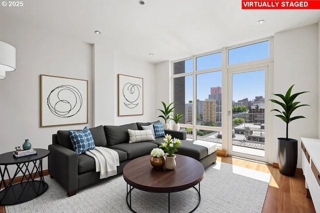 living area featuring expansive windows, wood finished floors, a view of city, and recessed lighting