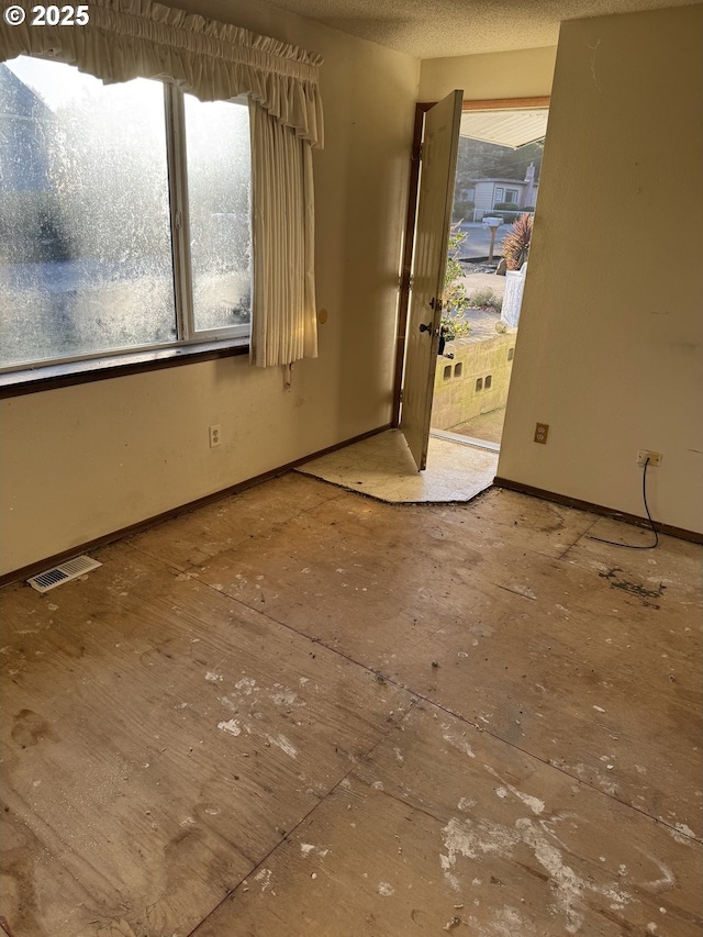 spare room featuring visible vents, baseboards, and a textured ceiling