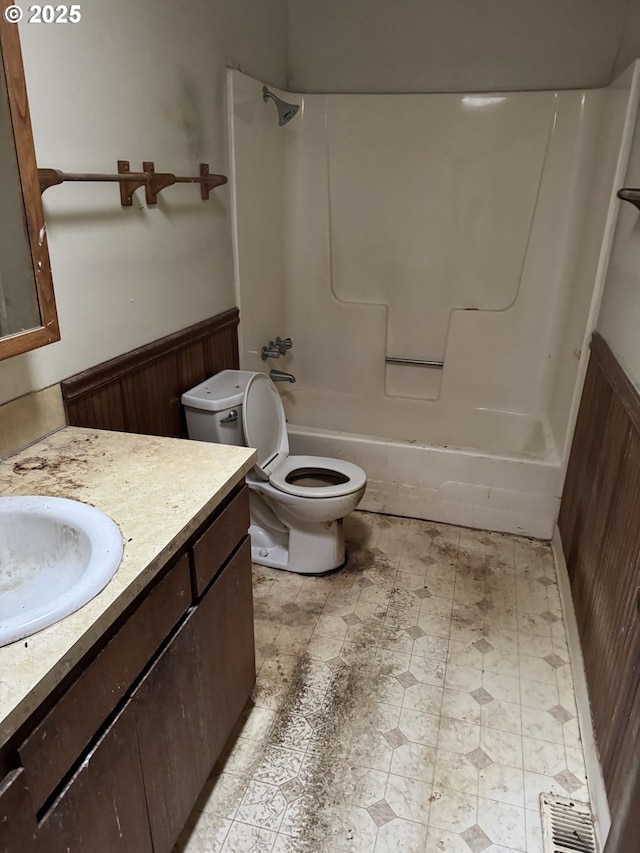 bathroom featuring visible vents, toilet, wainscoting, bathtub / shower combination, and vanity